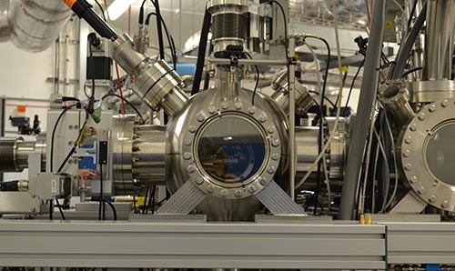 One of the accelerator beamlines made of stainless steel with multiple tubes, wires, and a central viewing window